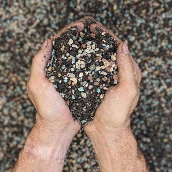 A person holding a large scoop of cactus soil in their hands