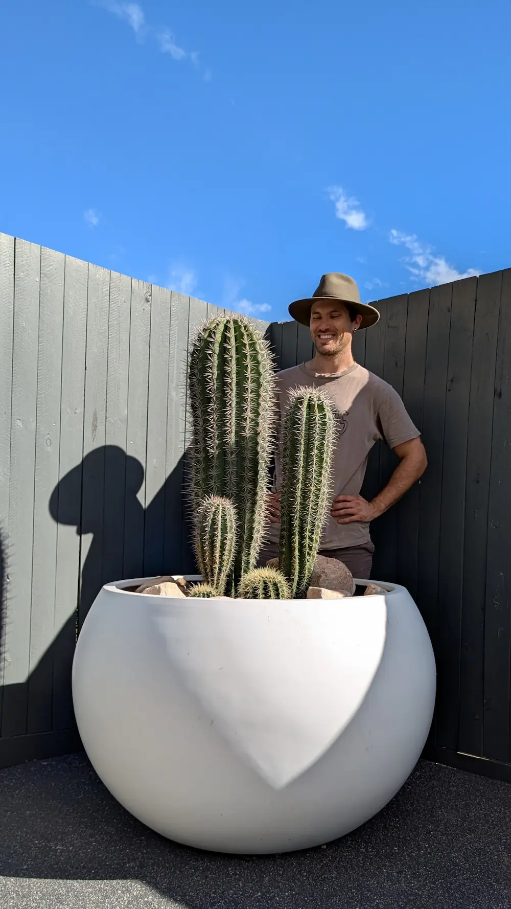 A man standing next to a large white pot with cacti in it